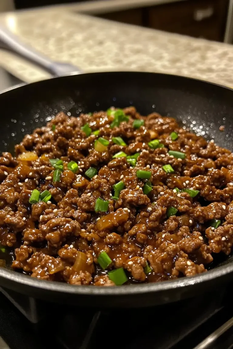 A skillet filled with savory Mongolian ground beef, garnished with chopped green onions and sesame seeds, cooked to perfection.