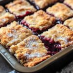 Freshly baked cherry pie bars in a baking pan, dusted with powdered sugar