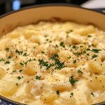 A pot of creamy potato soup topped with fresh parsley and black pepper, served hot and ready to eat.